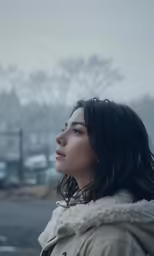 a woman standing outside in the rain with her head down