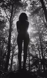 a woman in a black and white photograph standing between trees