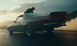 the man is sitting on the hood of a car