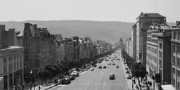 a street filled with traffic and buildings next to a forest