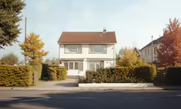 white three story house with some bushes around it
