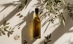 olive oil in a bottle hanging on the wall with fresh herbs