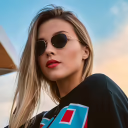a blonde woman in sunglasses wearing black and blue outfit