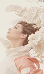 a girl is looking up and flowers are blooming in the background