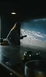 a woman is sitting on the counter pointing to something in front