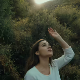 woman standing outside with her hand raised in the air