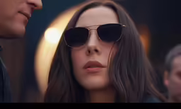 a man and woman look towards the camera in sunglasses