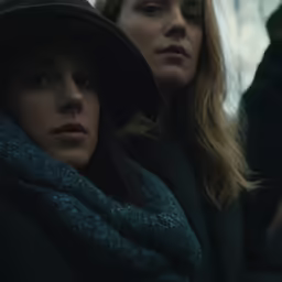 two women stand next to each other wearing scarves