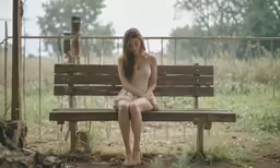 the young woman is seated on the bench and alone