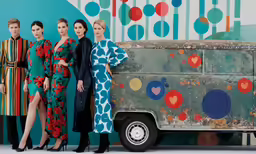four women in colorful dresses standing in front of a food truck