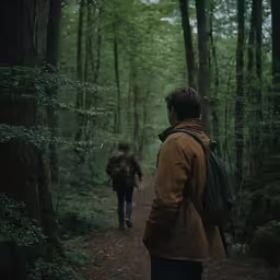 a man wearing a brown jacket walks next to a person carrying a backpack