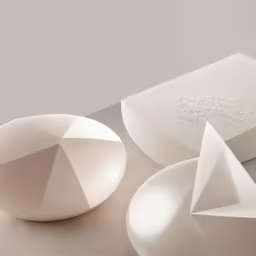 three white geometric shapes sitting on a gray surface