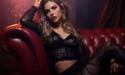 the woman in stockings is posing on a red couch