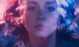a woman with blue eyes and curly hair with waves coming from her
