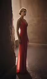 a beautiful woman in a red dress standing by a wall
