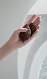 a persons hand holding two chocolate donuts