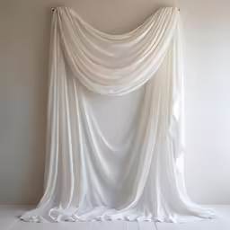 a white curtain that has some kind of fabric draped over it