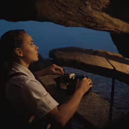 a woman is sitting on rocks looking into the sky