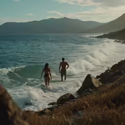 two people swimming in a body of water next to a rocky shore