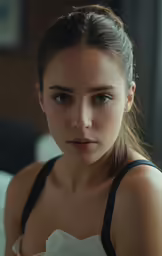 a girl wearing a tank top looks pensively at the camera