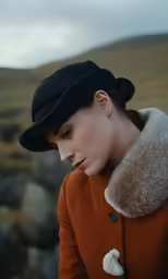 a woman wearing a hat and coat with an ear ring