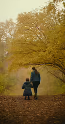 woman and child standing in a forest surrounded by leaves