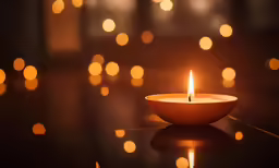 small candle is lit in a bowl on a table