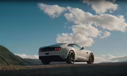a white sports car on a gravel road with mountains in the background