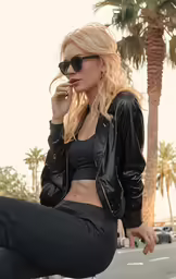 a blonde girl sitting on the street wearing black