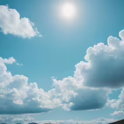the sun shining over a hill near a sea