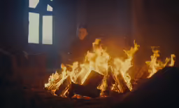 a person sitting in front of fire with windows
