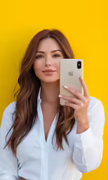 a woman is holding her iphone in front of a yellow wall