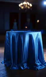 a blue table cloth draped around it, with an object blurred in the background