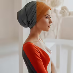 woman wearing an orange and grey top with her hair in a bun