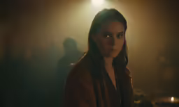 a woman standing in the middle of a room with a flashlight