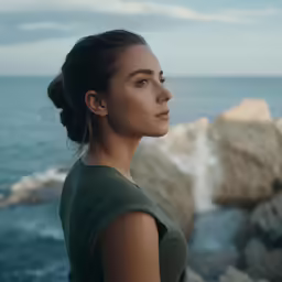 a woman standing on top of a cliff next to the ocean