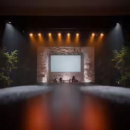 a room full of people sitting in chairs, and watching a screen