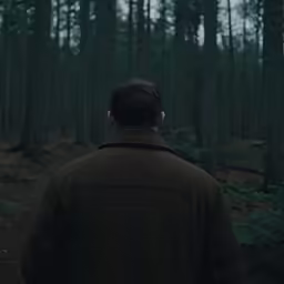 a man in the woods standing in front of trees