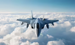 a military jet flies in the sky over clouds
