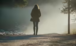 a woman wearing a long coat in a forest