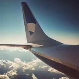 the wing of an airplane above a cloud filled sky