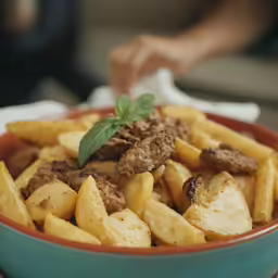 a blue bowl with a green lid filled with lots of food