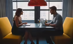 two people sitting at a table with their laptop