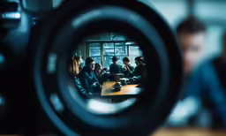 a camera lens with a group of people sitting at a table