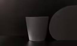 a large gray cup on a black surface next to a circular object