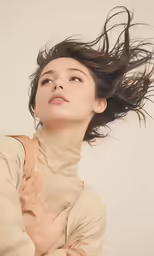 a young woman is holding her hair in the wind