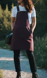 a woman stands and looks off to the side while holding a bag