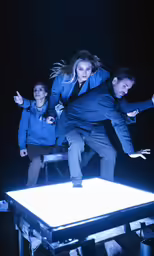 three people standing in front of an interactive table