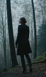 a person standing in front of a tree with their hands in their pockets