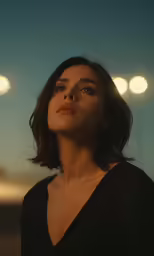 a woman in black dress with lights in the background